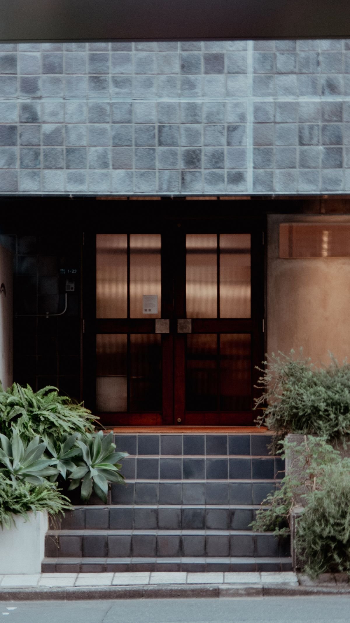 Urban building entrance with a tiled facade and greenery