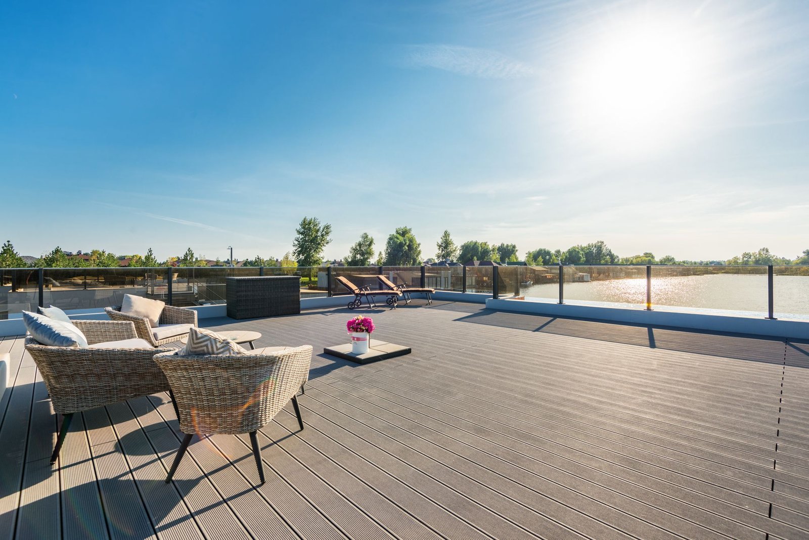 Spacious rooftop deck with rattan lounge furniture overlooking water