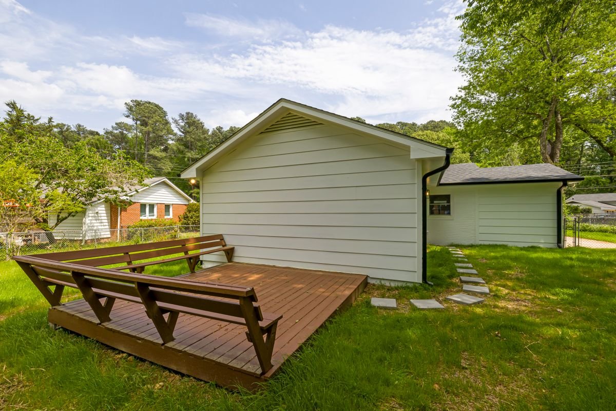 Wooden deck in backyard surrounded by lush greenery