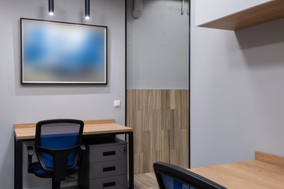 Desk workstation with blue task chair beside light timber panelling and a framed picture