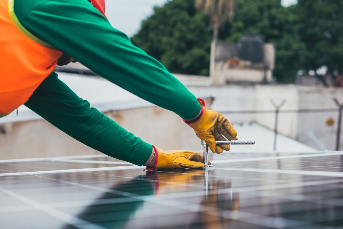 Close-up of a technician securing solar panel mounting hardware on a rooftop
