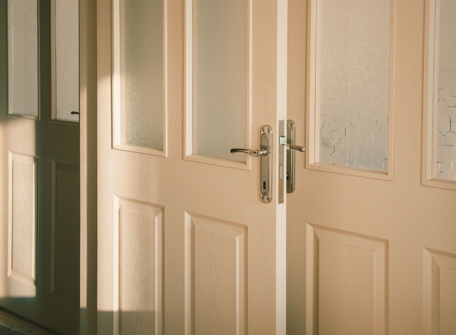 Elegant wooden doors with frosted glass panels illuminated by sunlight