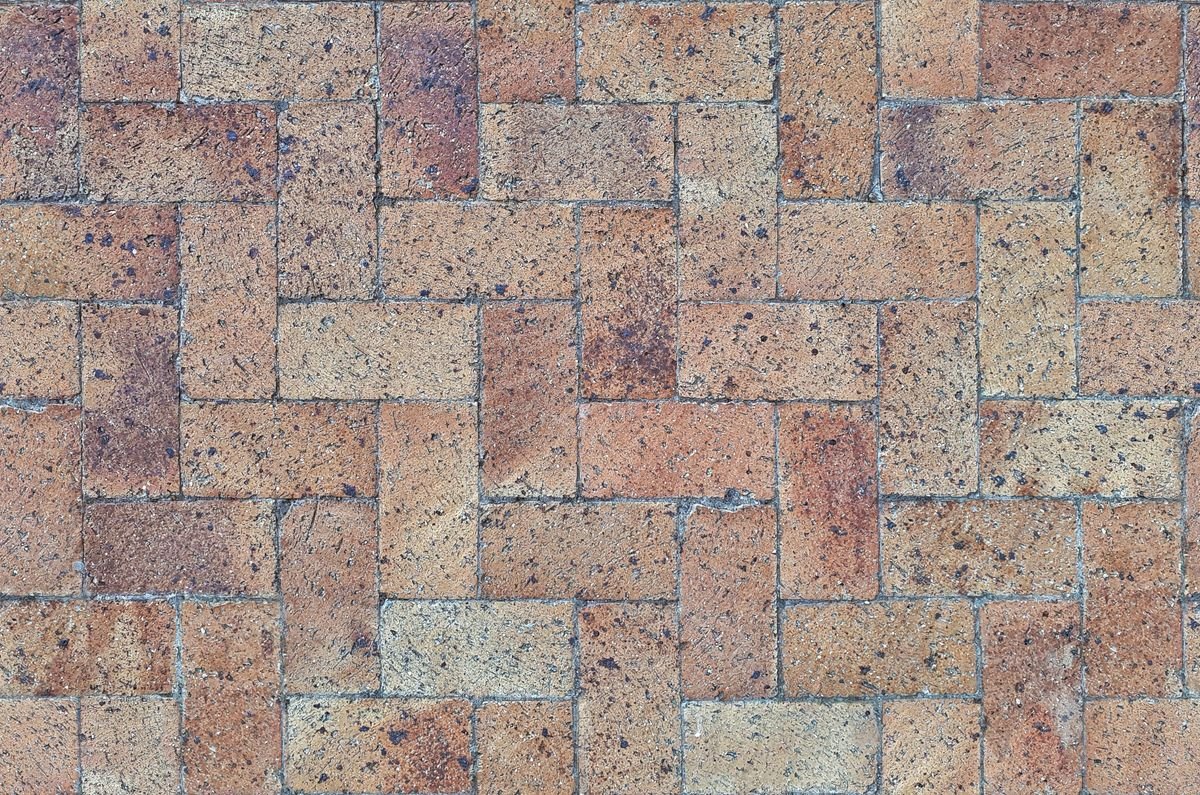 Close-up of red-toned interlock pavers laid in a herringbone pattern