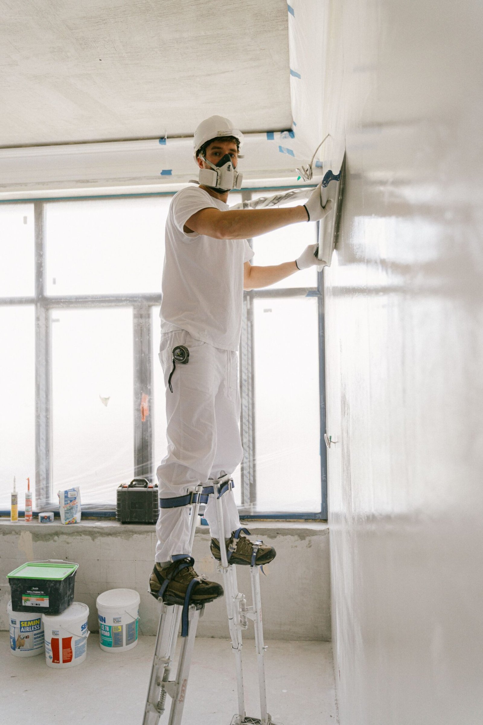 Construction worker smoothing a drywall partition using safety gear