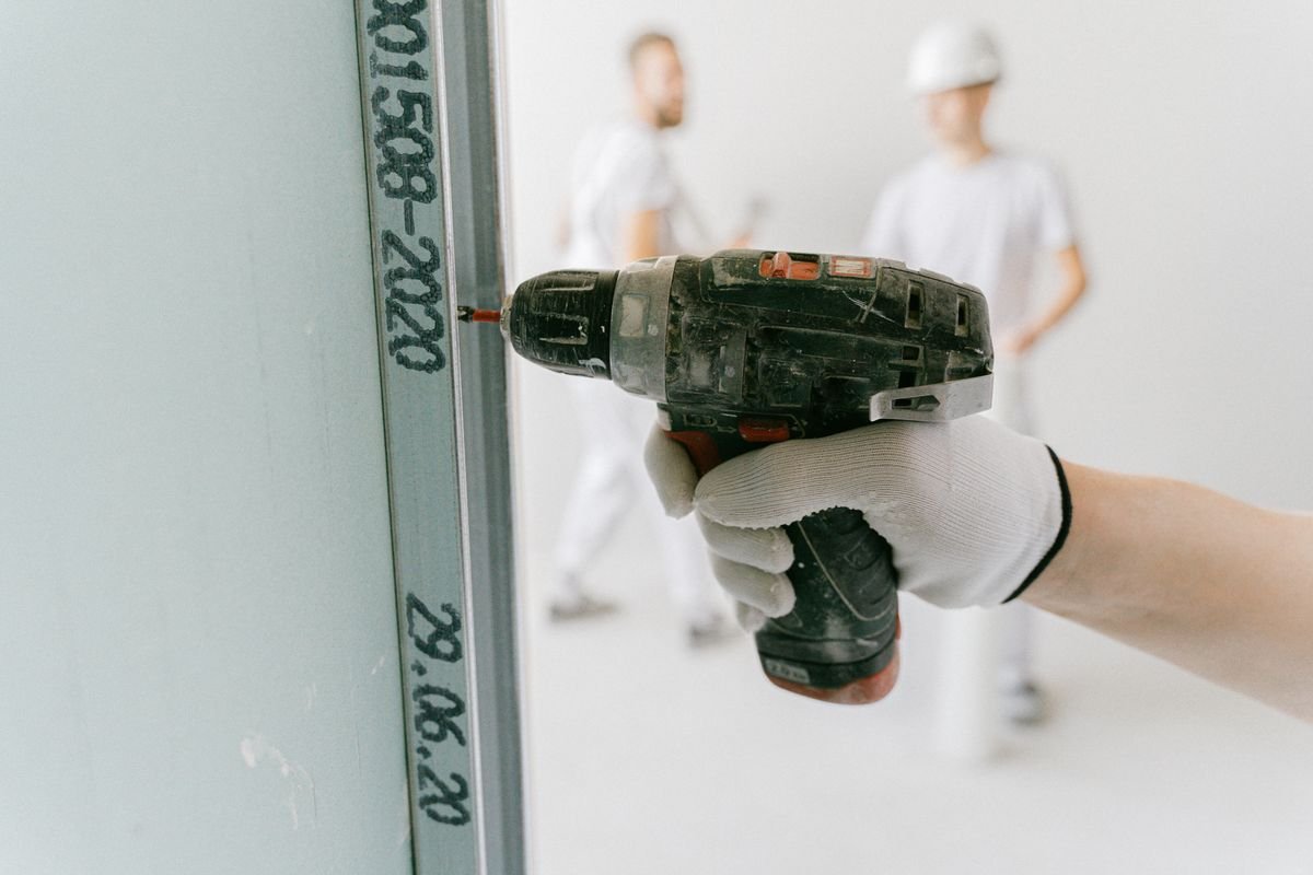 Construction worker using a drill on a drywall partition
