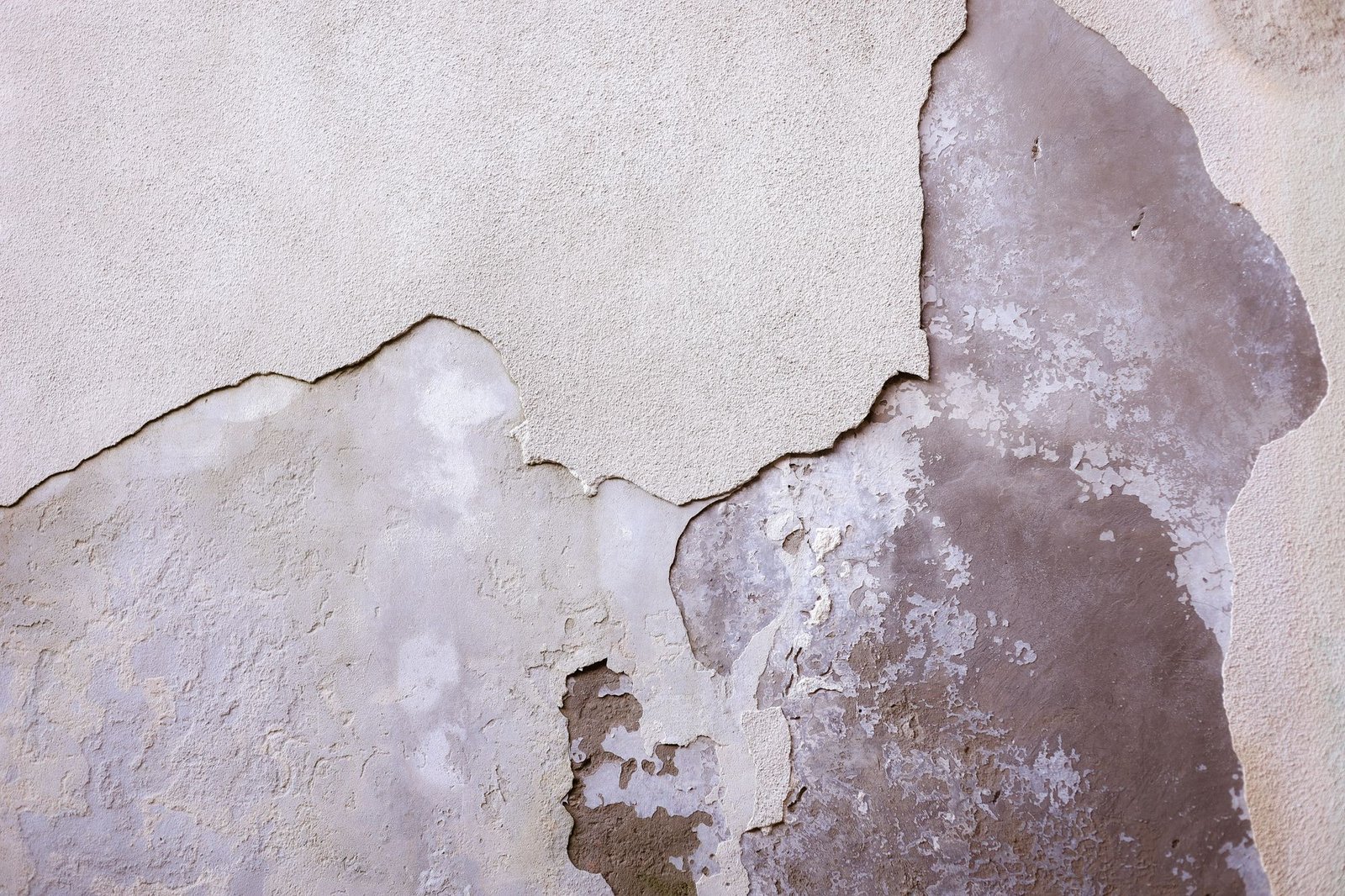 Large section of drywall plaster damaged and peeling away from the wall in distinct layers