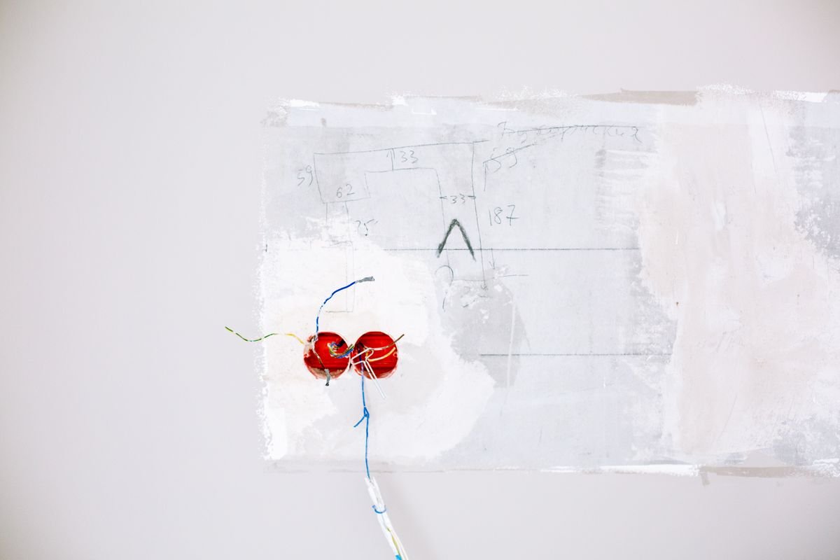 Drywall patch cut into a wall exposing electrical wiring behind it