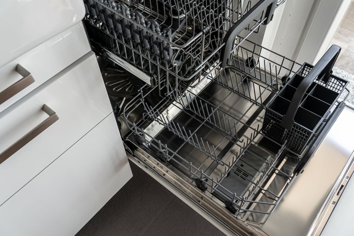 Empty stainless steel dishwasher open in a modern kitchen