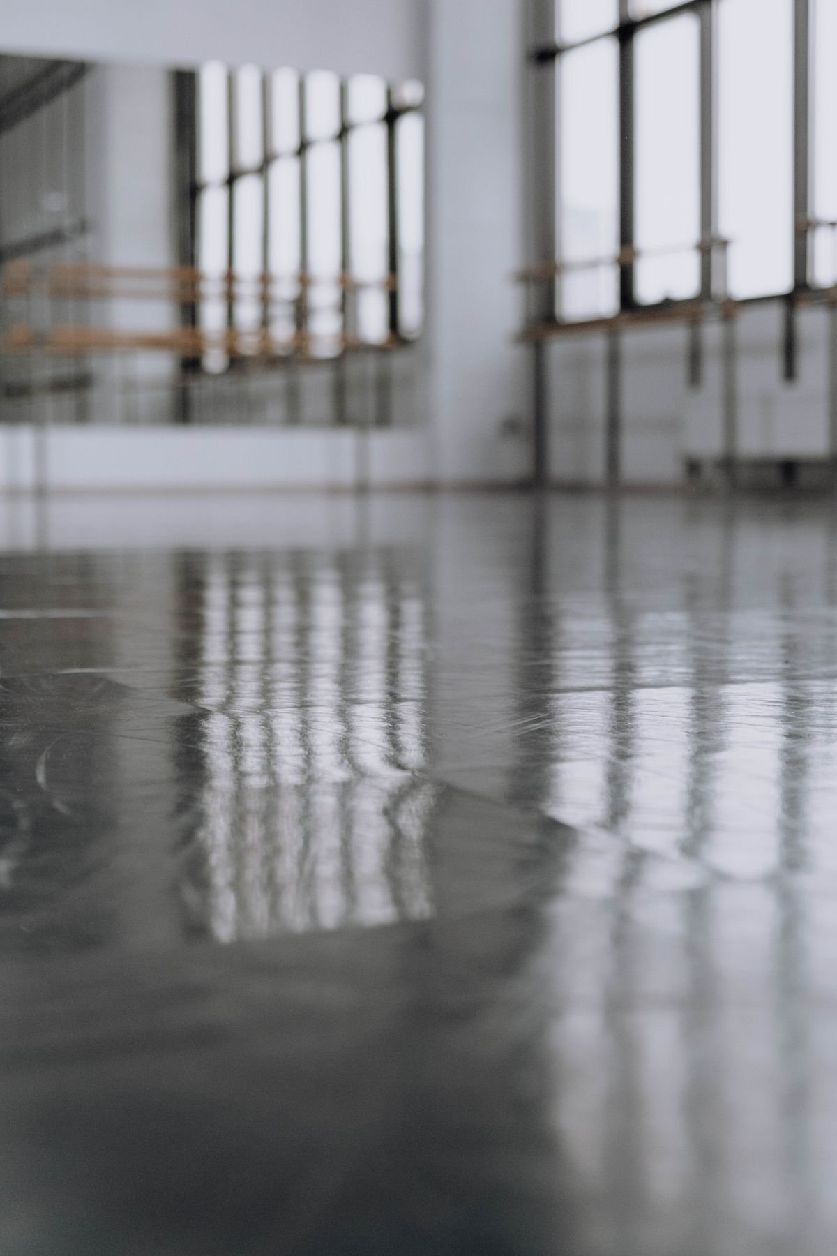 Dance studio with a smooth reflective floor, mirrors, and tall windows