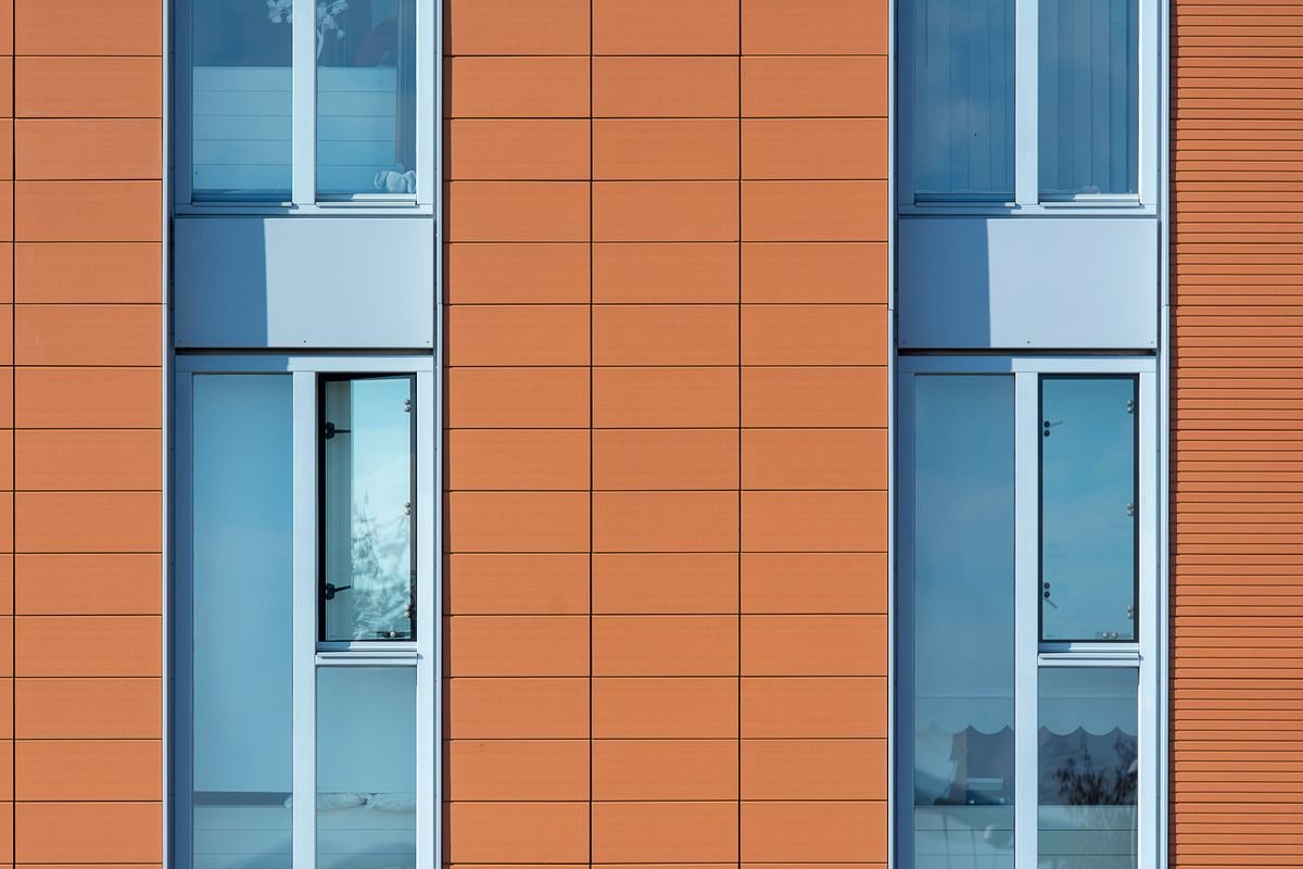 Terracotta-coloured panel cladding beside large windows on a modern building