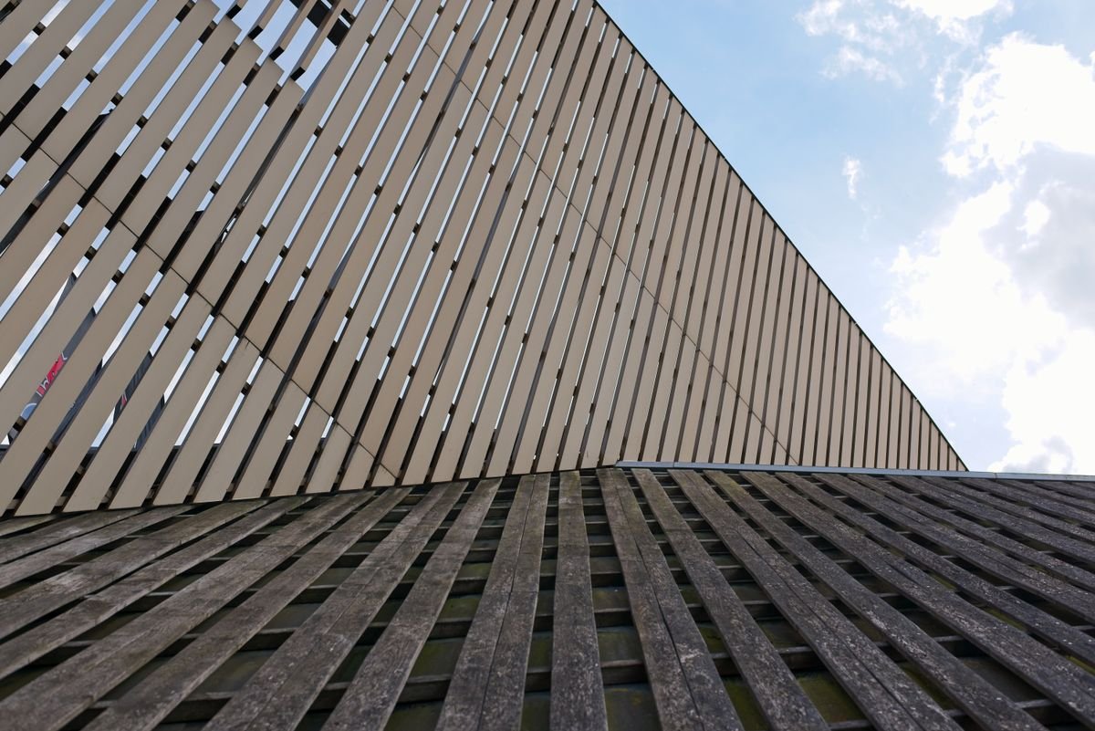 Building exterior clad in vertical wooden boards against a bright sky