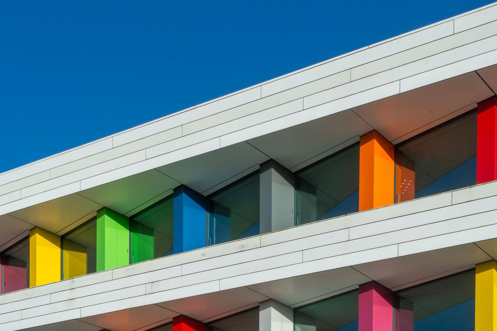 Vibrant building facade clad in colourful panels under a clear blue sky