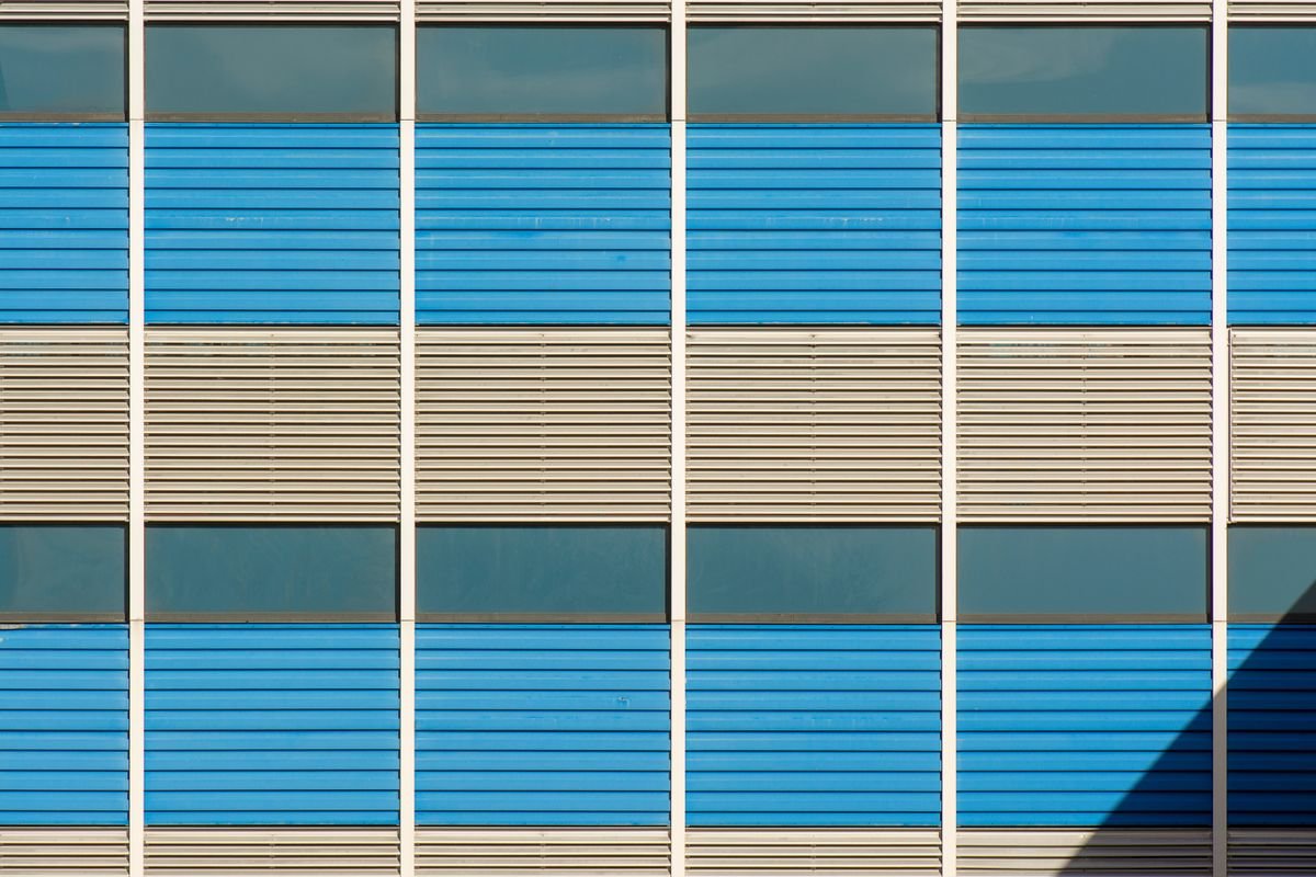 Modern building facade with blue and beige metal-stripe panels and windows