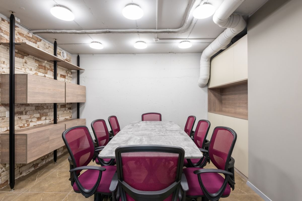 Meeting room with a flat tiled ceiling, round downlights, and exposed ducts