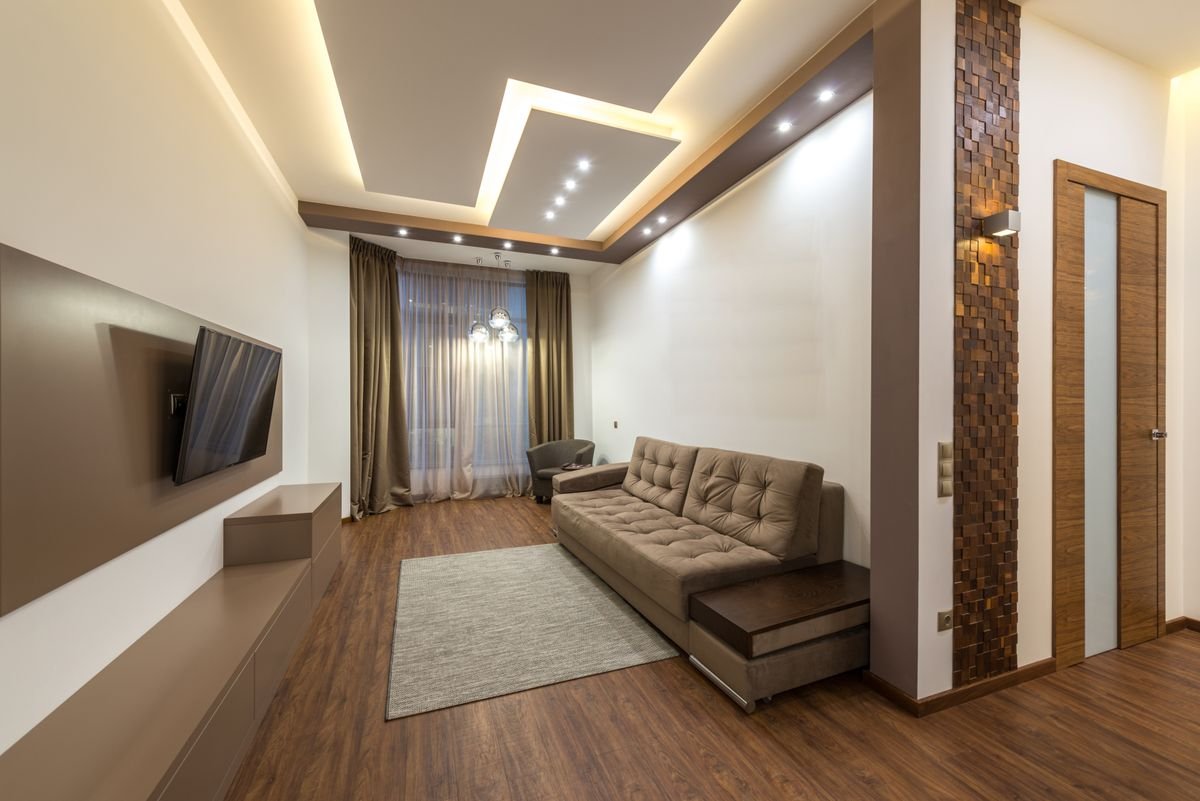 Living room with a stepped gypsum false ceiling, cove lighting, and recessed spotlights