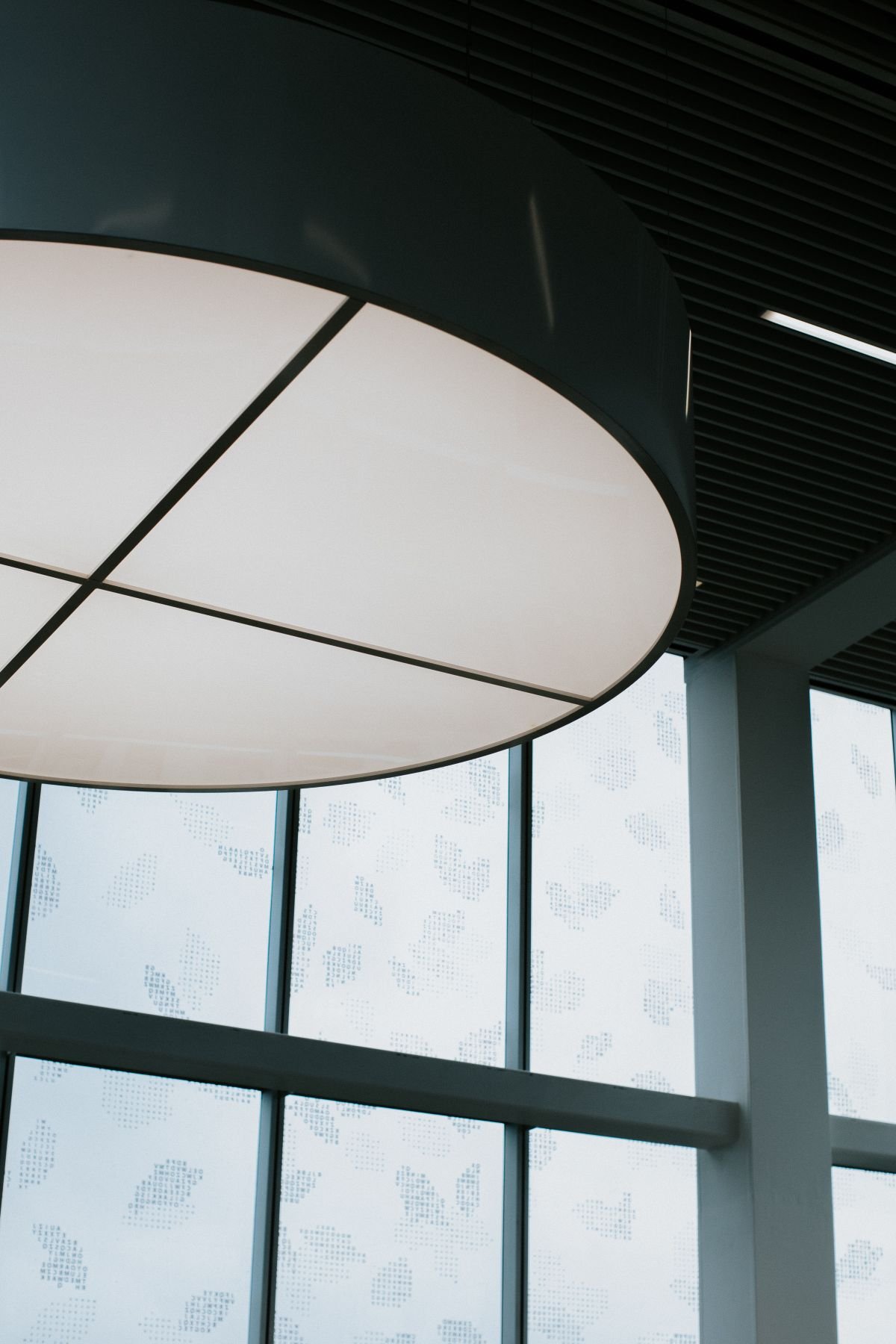Large round suspended ceiling panel above floor-to-ceiling windows
