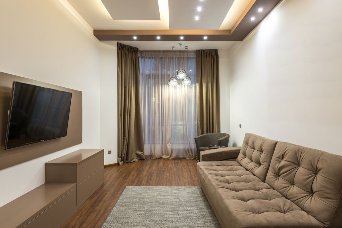 Finished living room with a gypsum ceiling, lit cove, and recessed spotlights