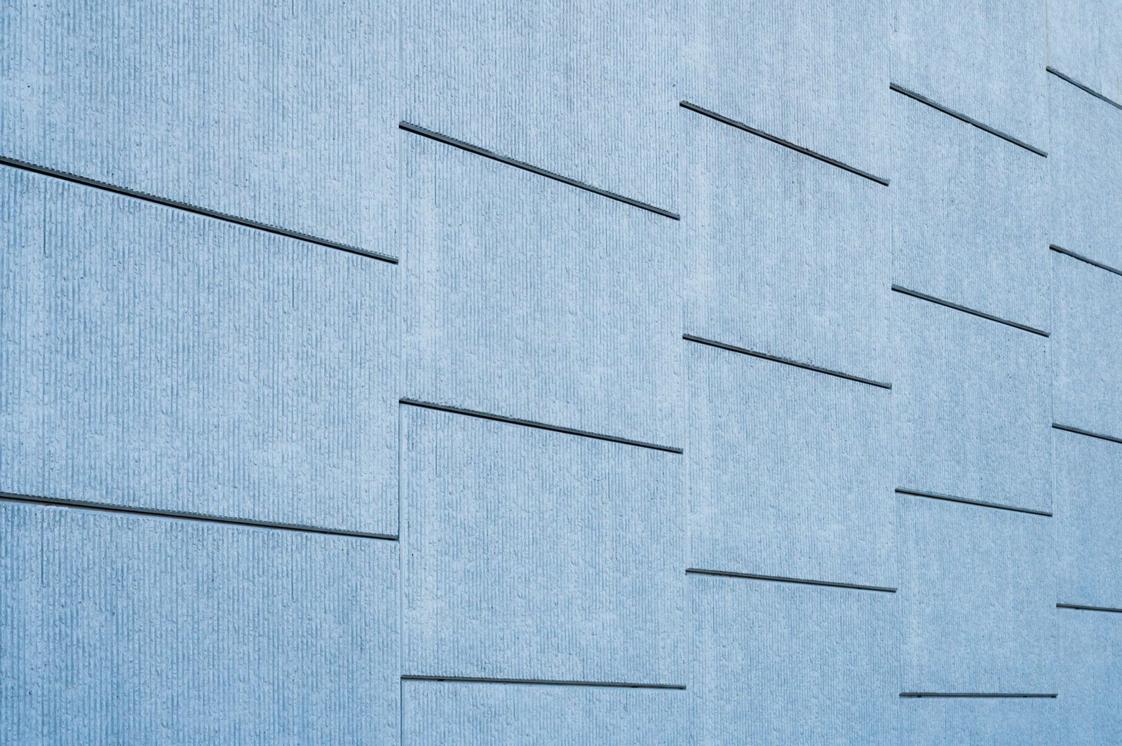Blue-tinted concrete wall with sleek geometric lines on a modern building