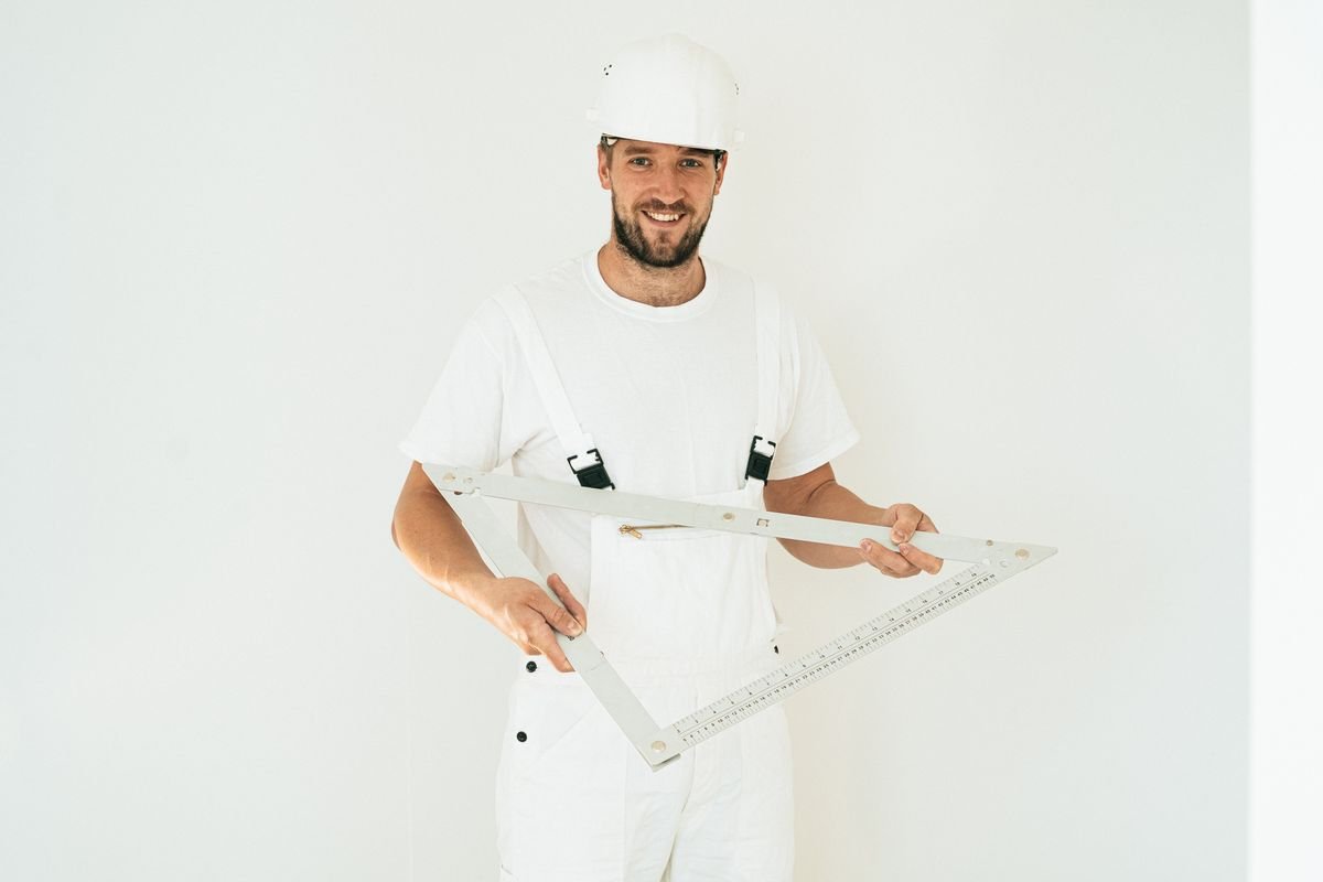 Technician in a hard hat setting out a wall with a large set square