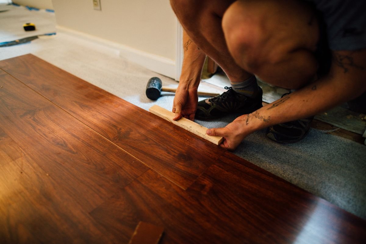 Worker installing laminate flooring in an apartment