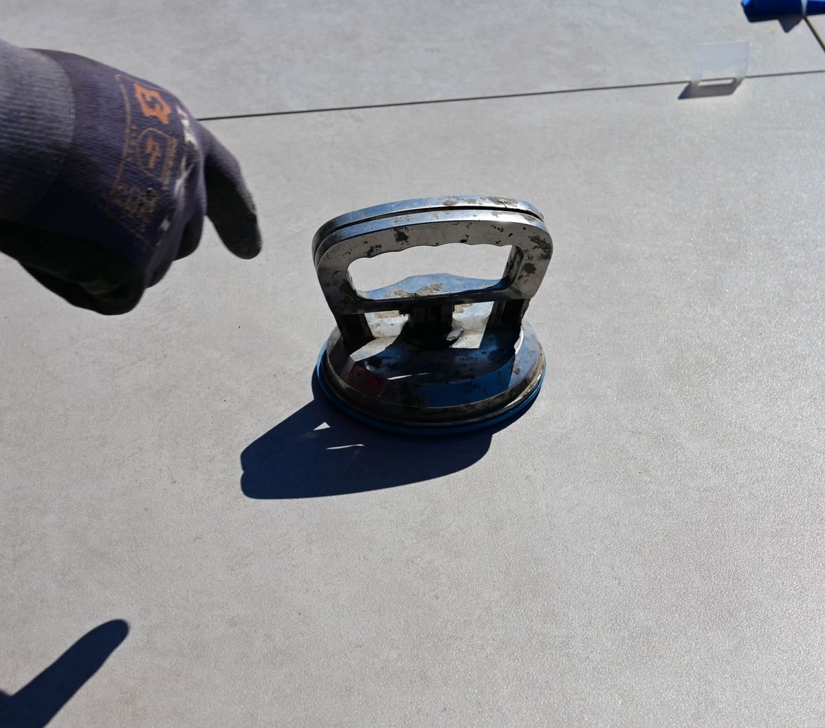 Suction-cup tile lifter resting on a large porcelain floor tile