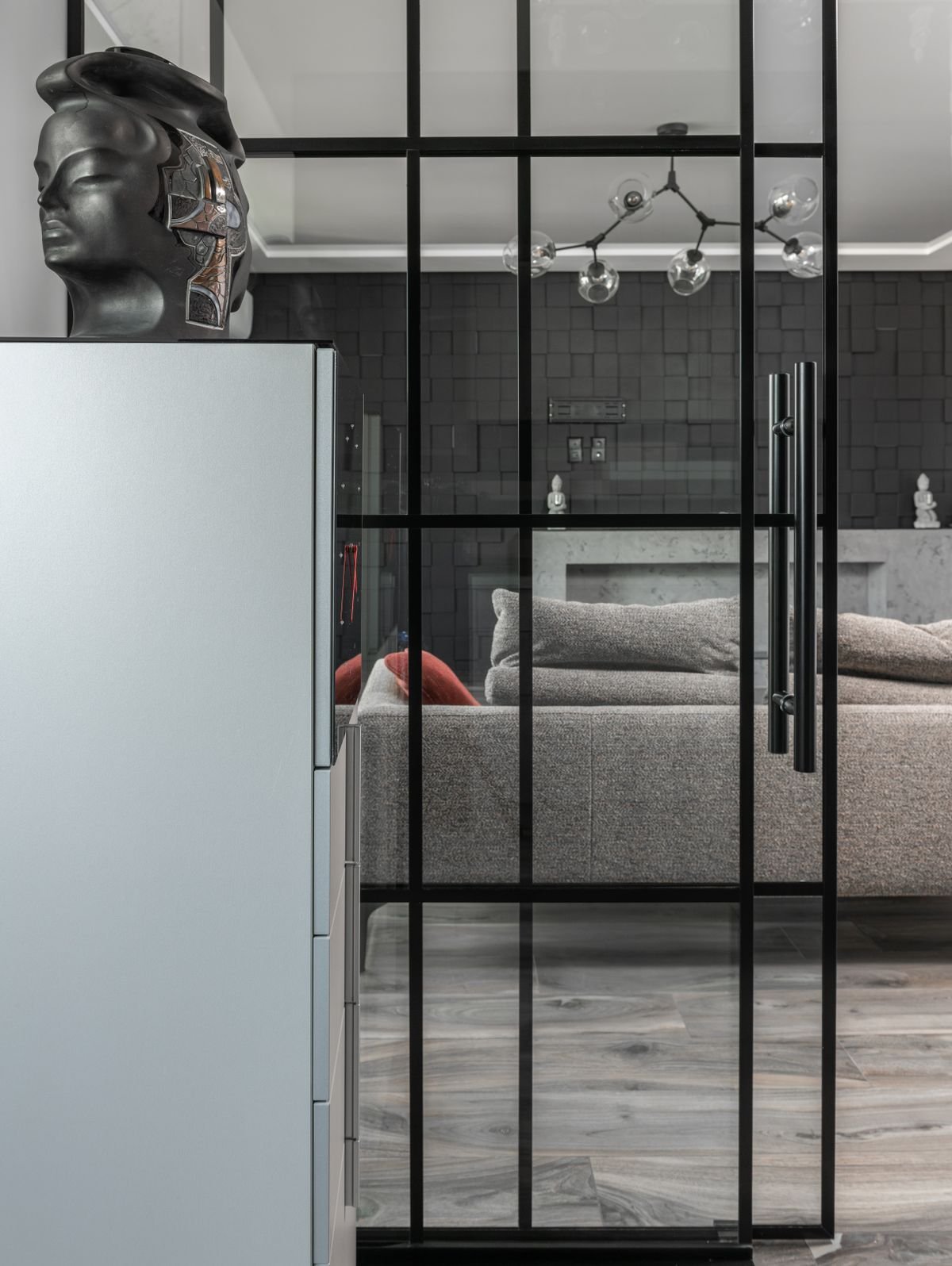 Grey interior with a glass door set into a partition wall and a head sculpture