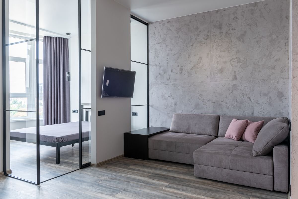 Living room with decorative cushions on a couch, a TV, and a glass panel beside the wall