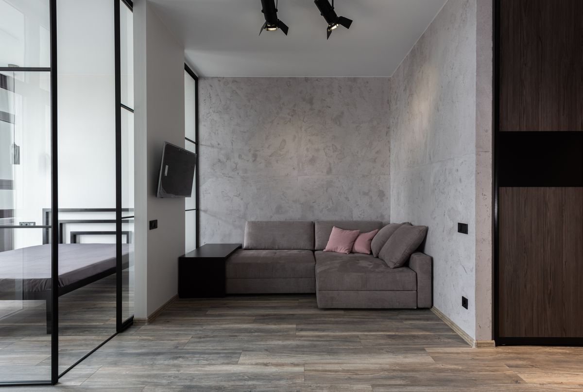 Living room with a soft sofa and cushions in front of a smooth white partition wall and TV