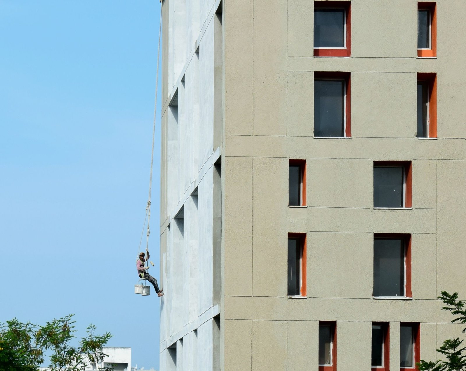 Professional painter working on a rope access system painting a tall building facade