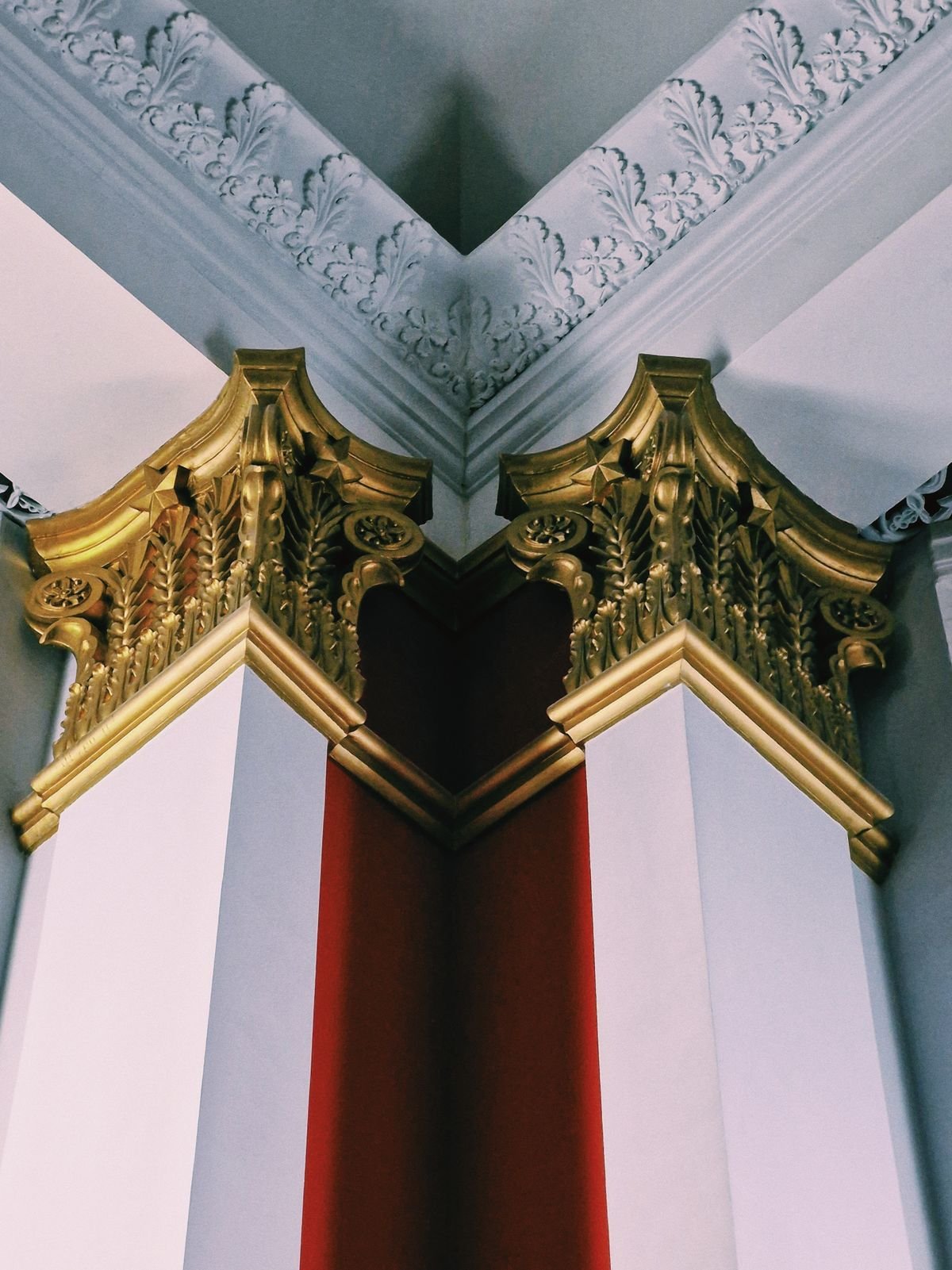 Gilded cornice and capital details against white and red walls