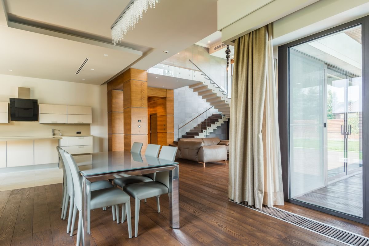 Dining area beside a feature staircase with timber panelling and floor-to-ceiling glazing