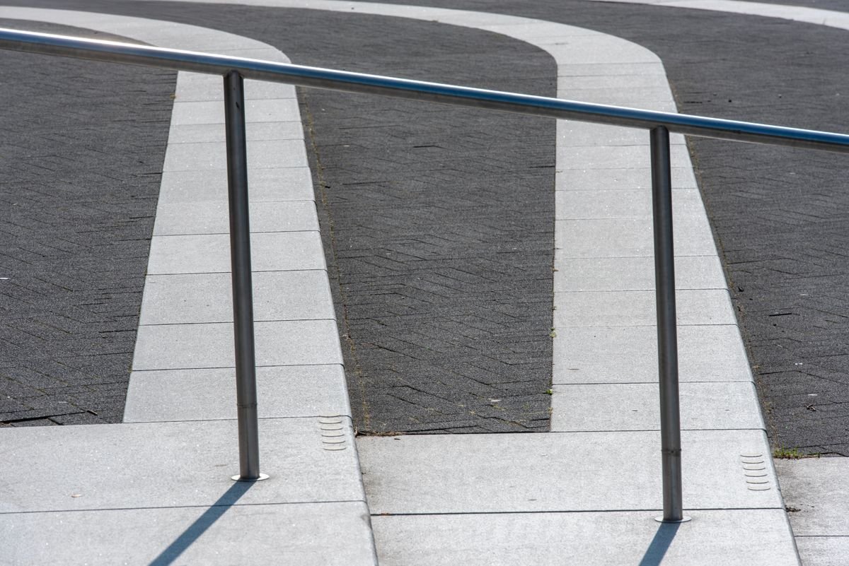 Paved walkway and steps with a metal handrail and crisp paver edges