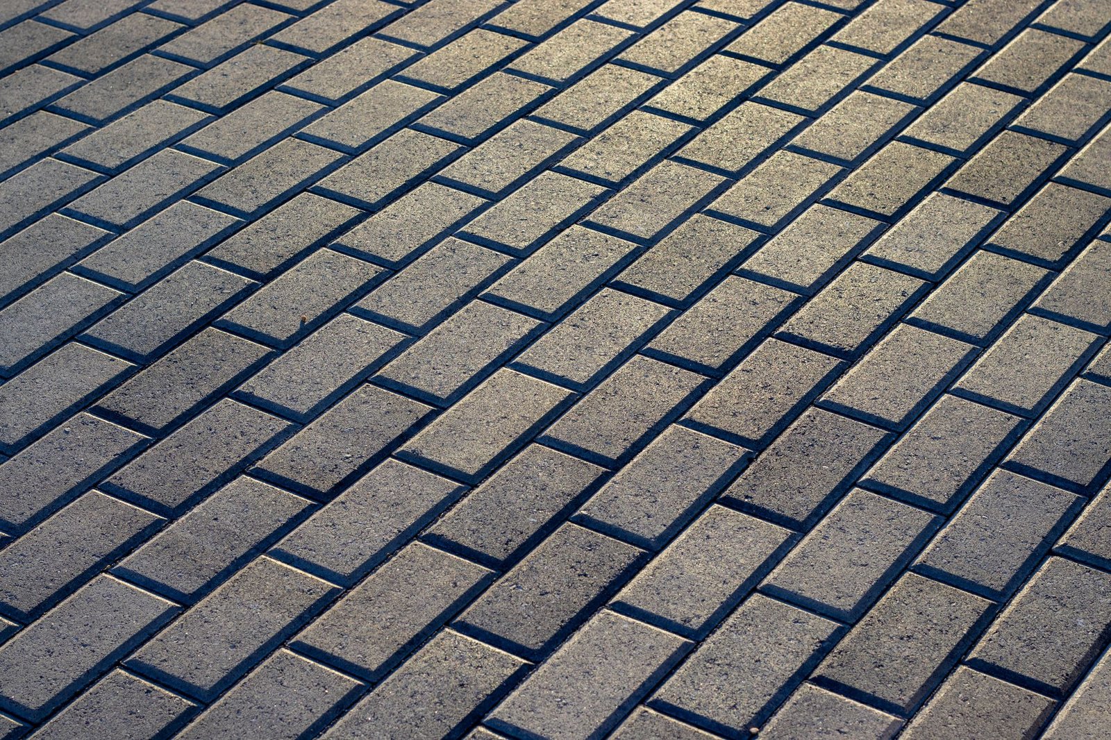Neatly laid interlock brick pavers in a tight, even herringbone-style pattern