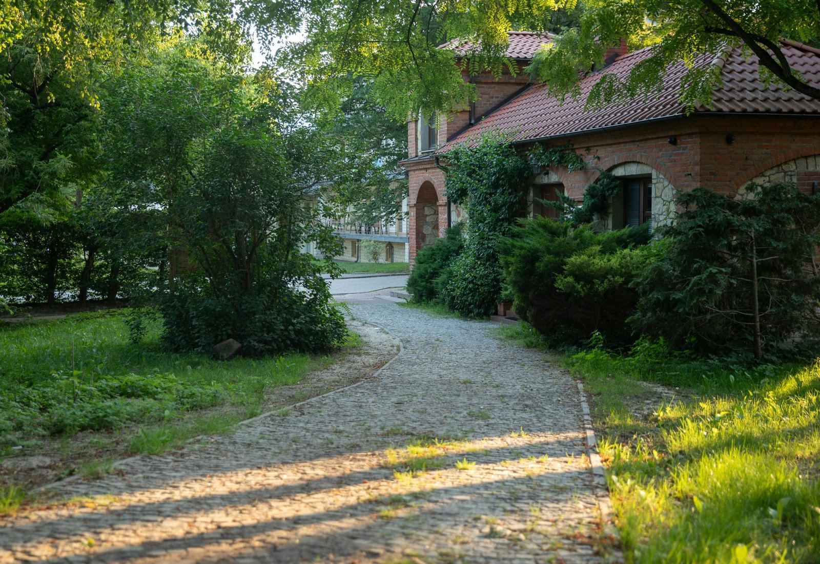 Stone house with a paved cobblestone driveway winding through mature trees