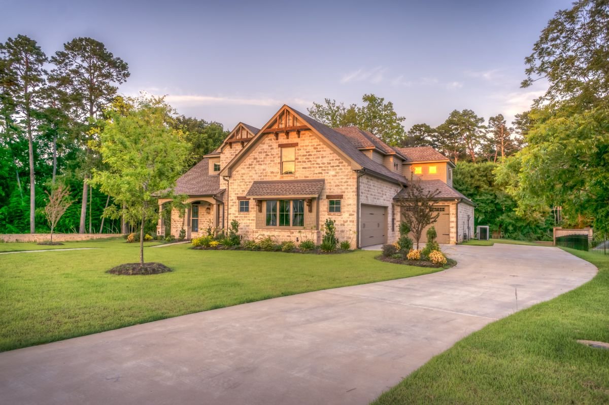 Stone bungalow with a curved paved driveway and landscaped lawn