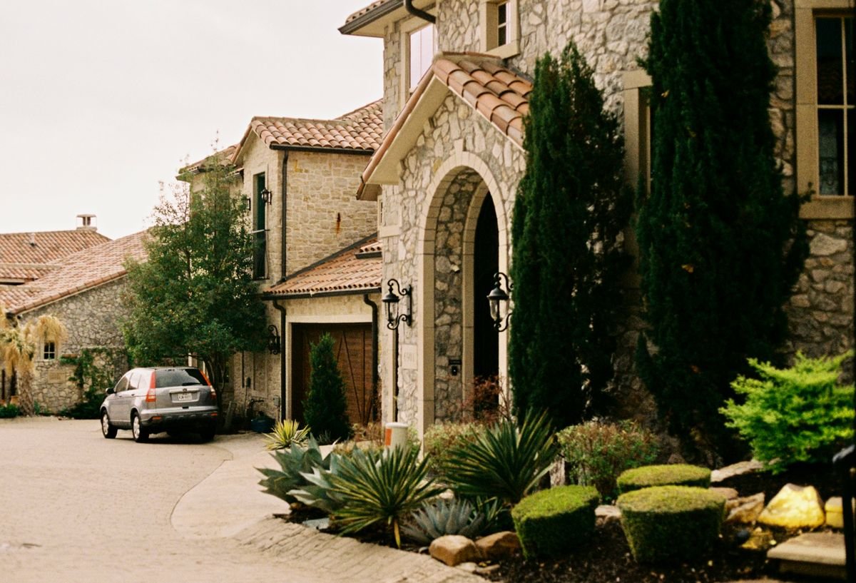 Stone mansion entrance with paved driveway and gated access