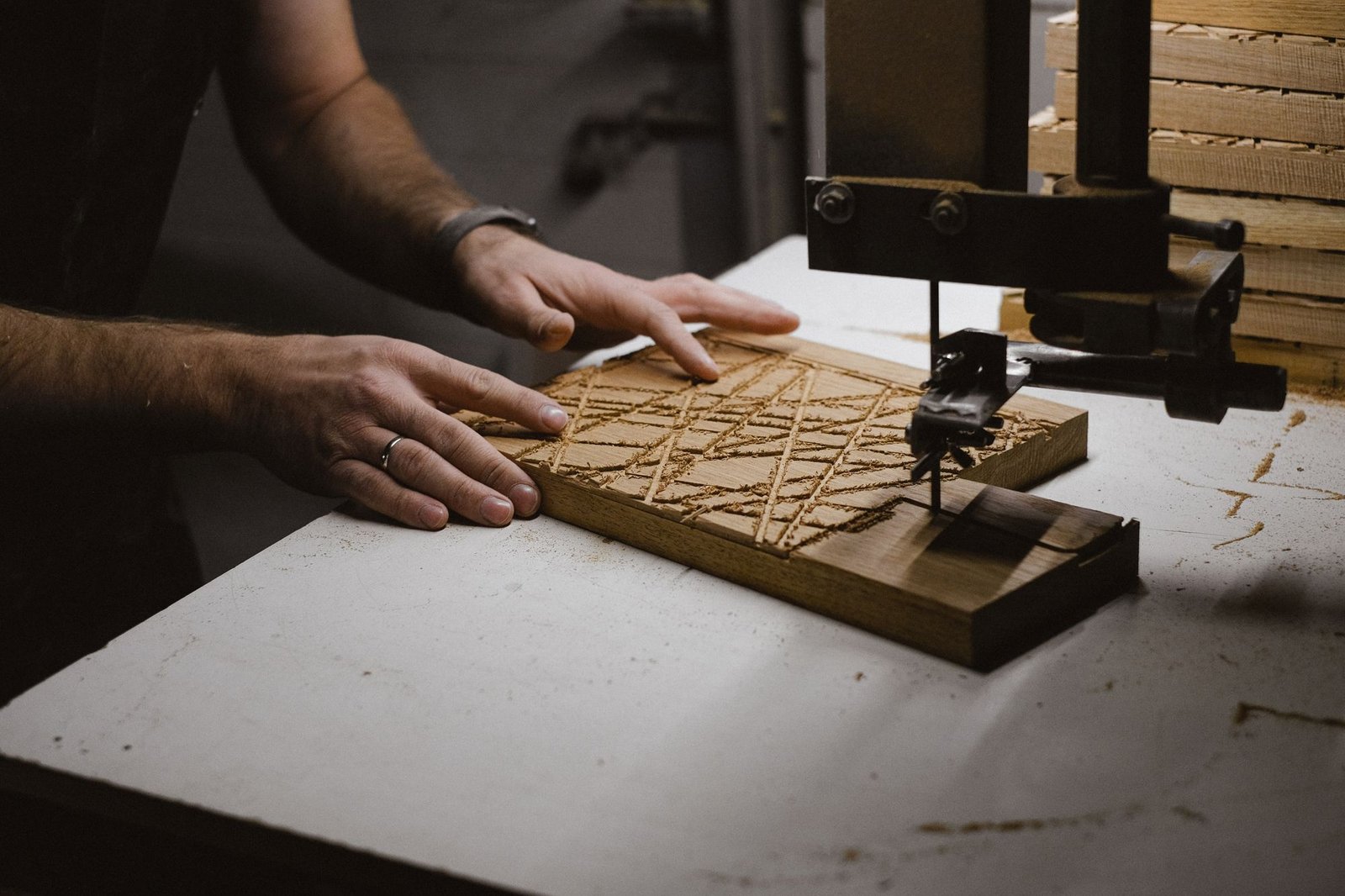 Craftsman using a bandsaw machine to create a pattern on a wooden plank in a workshop