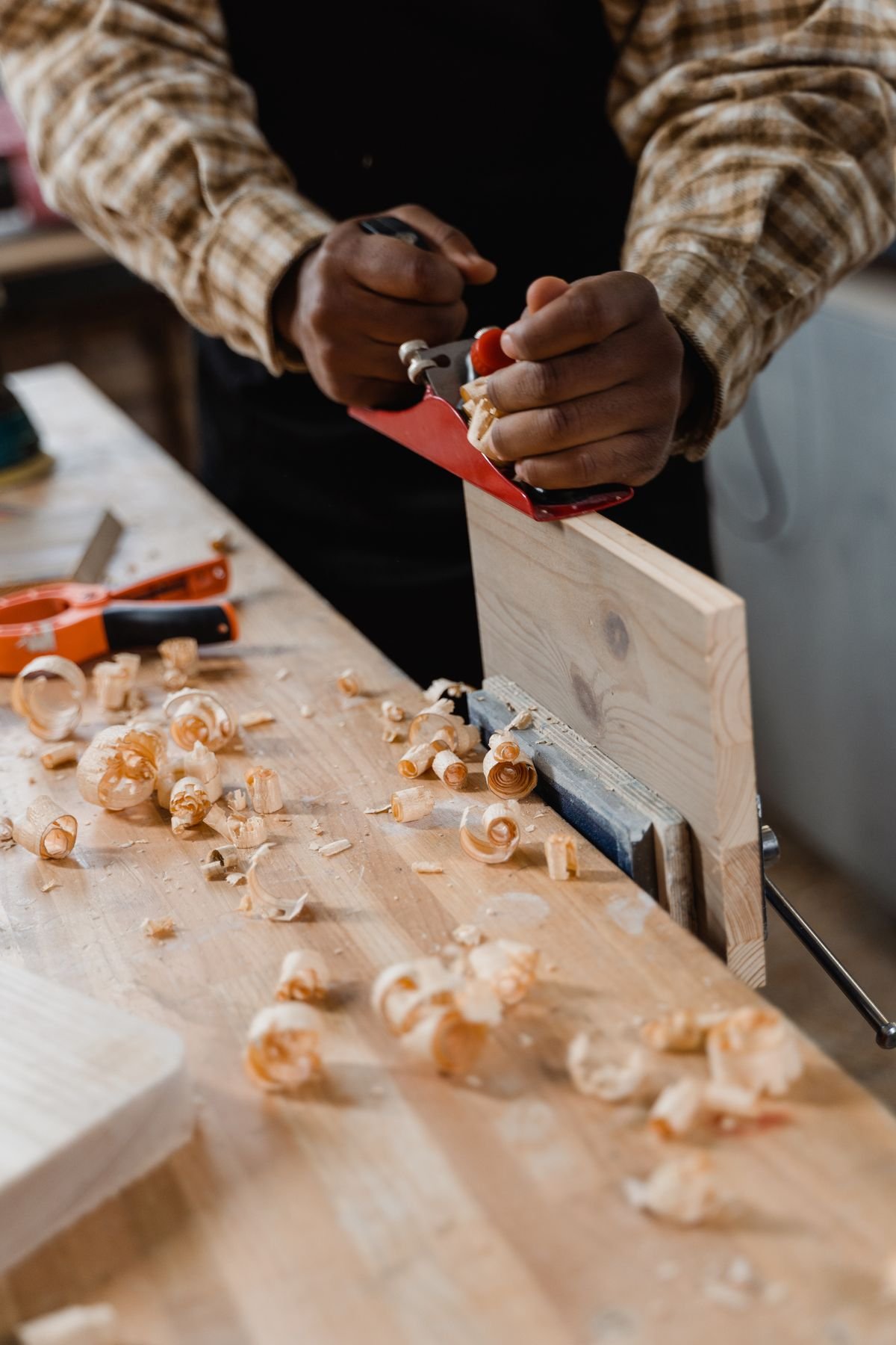 Carpenter shaping wood with a planer in a workshop