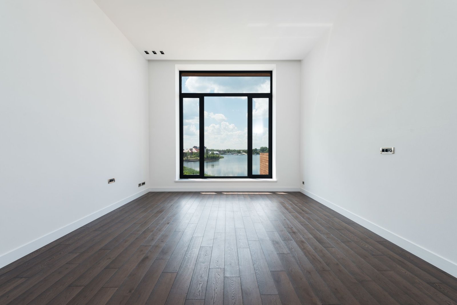 Interior of modern spacious room with wooden laminate floor, white walls, and panoramic windows