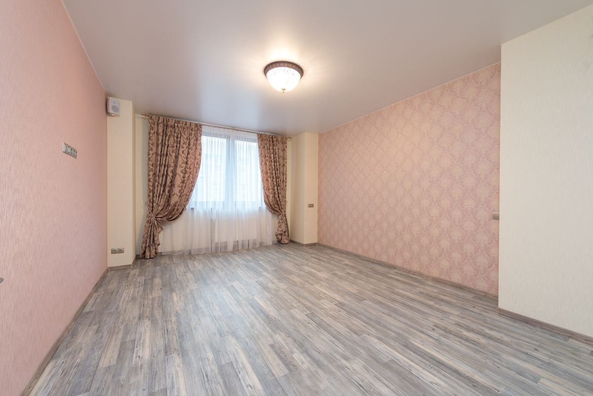 Empty spacious room with laminate flooring and colorful curtains