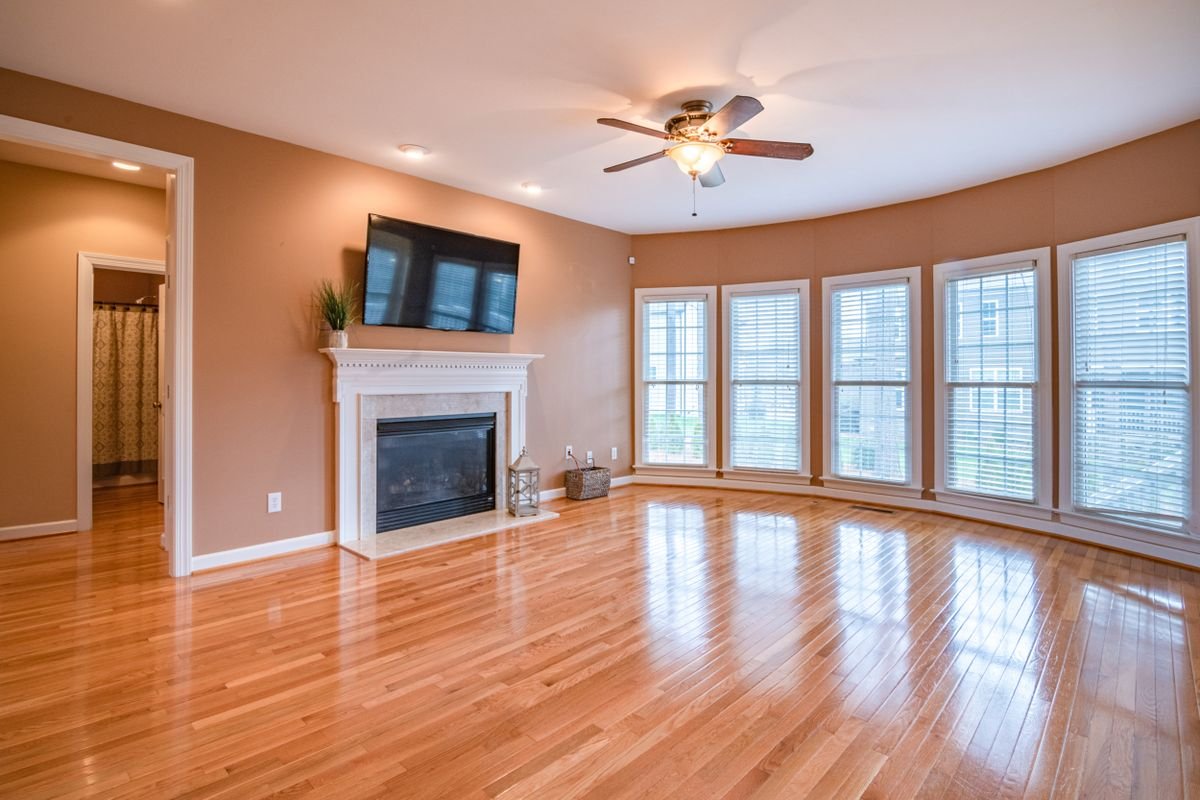 Bright living room with laminate floors, fireplace, TV, and ceiling fan