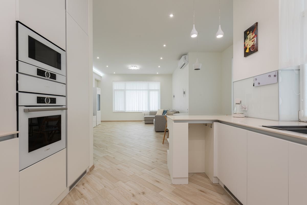 Interior of contemporary flat with clean laminate flooring and white furniture