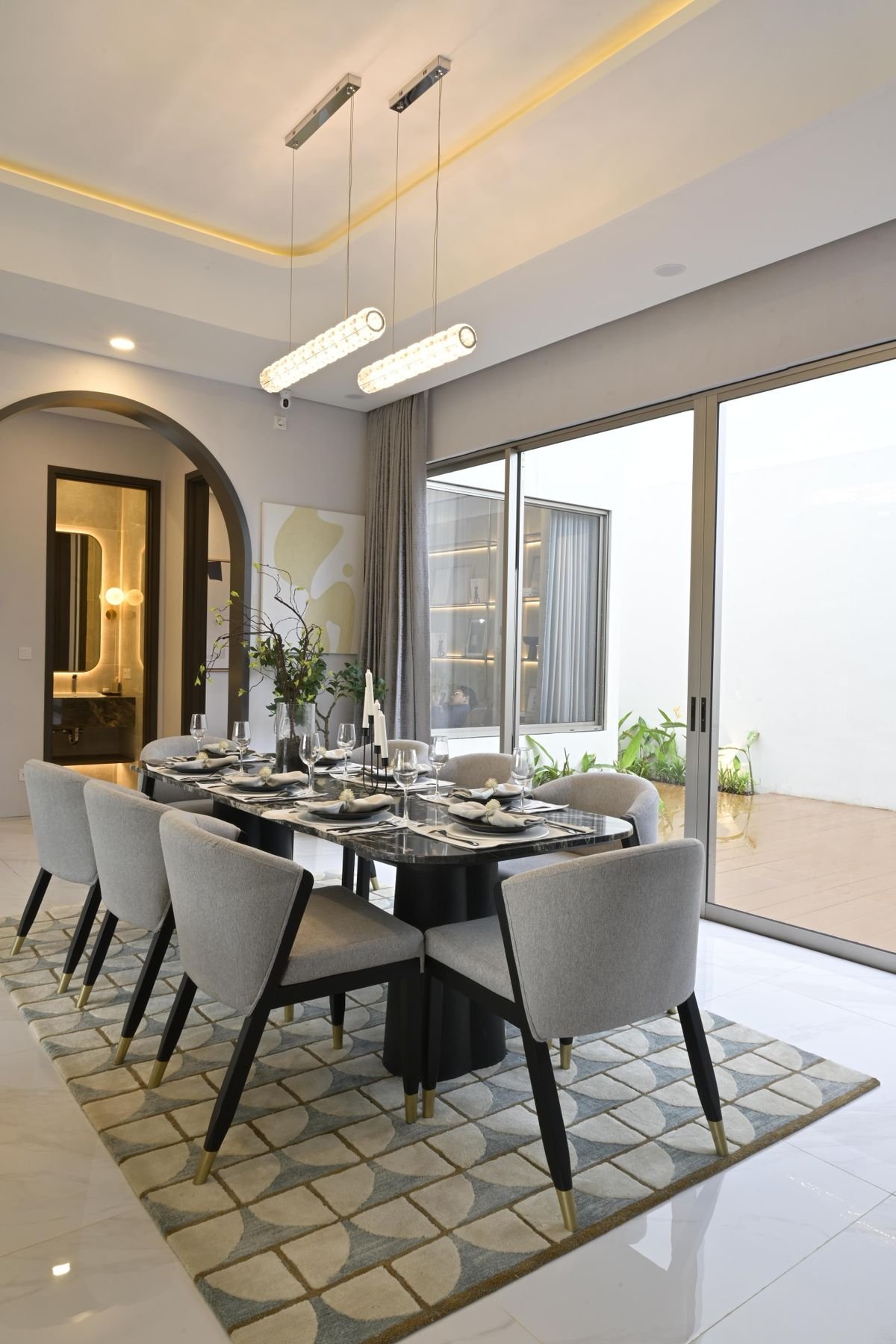 Luxury dining room with a long table, pendant lighting, and floor-to-ceiling windows