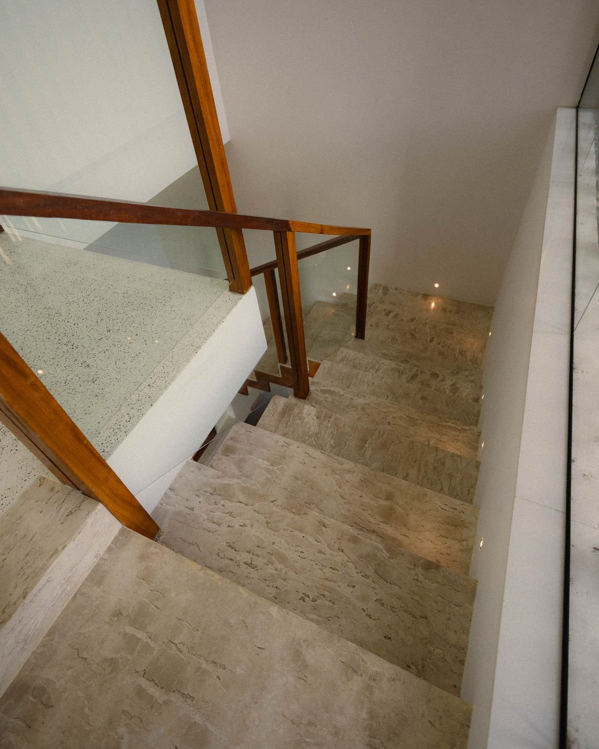 Modern marble staircase with a wooden handrail in a clean, polished interior