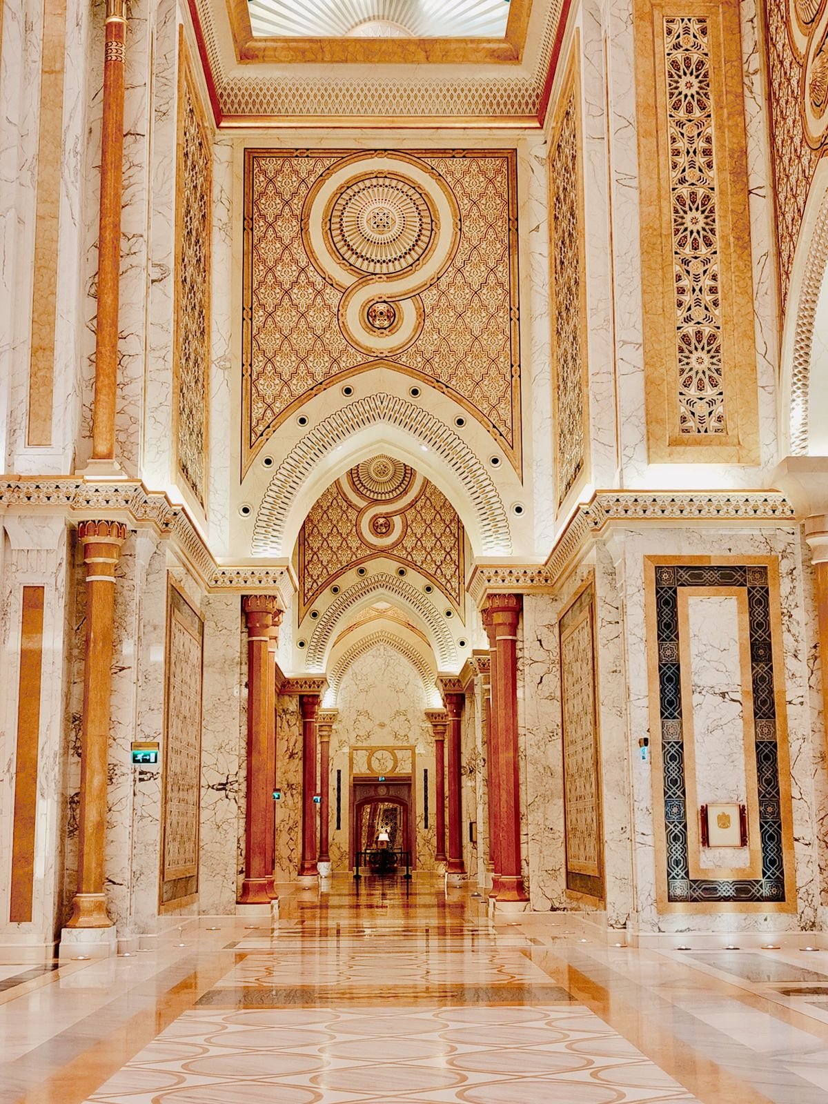 Opulent marble corridor with arches and ornate patterned detailing
