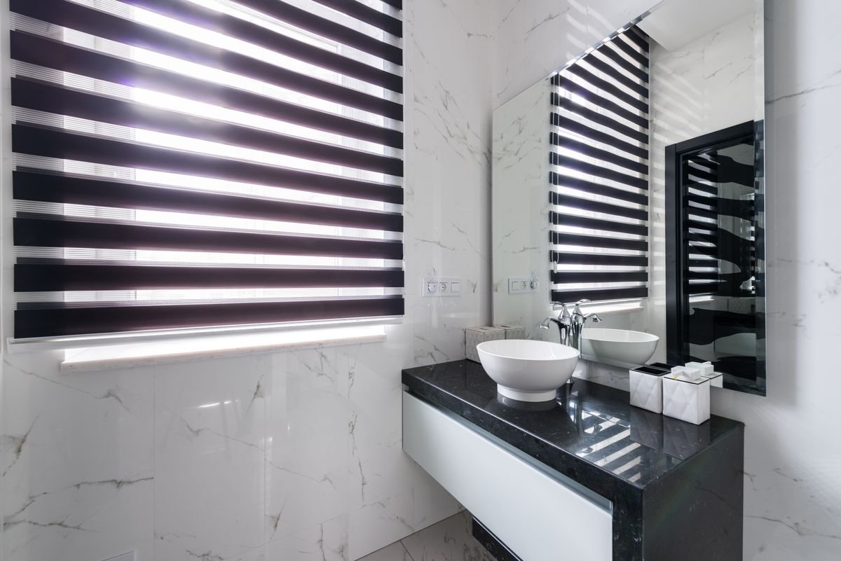 Modern bathroom with marble walls and a dark stone vanity countertop