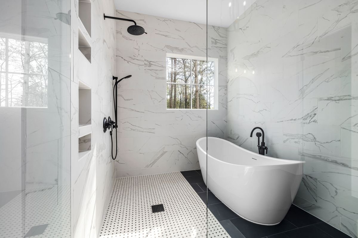 Modern walk-in shower and freestanding bathtub with marble wall cladding