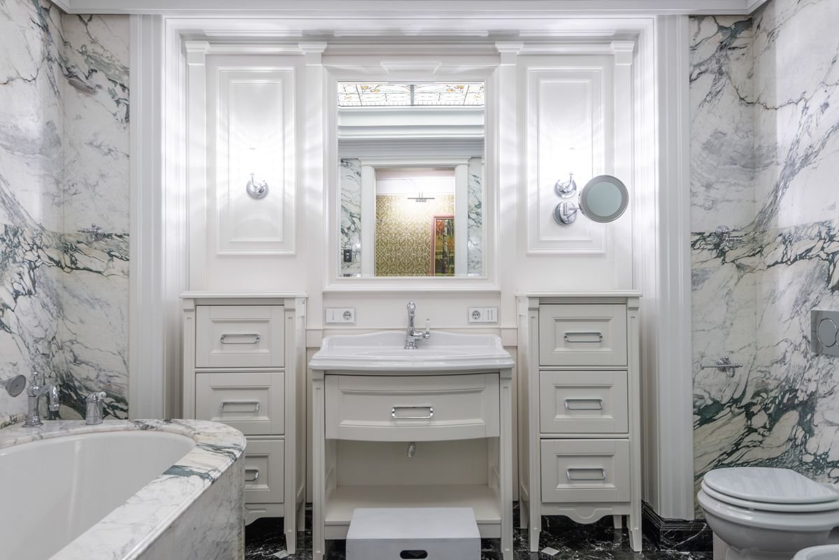 Marble-clad bathroom with fitted vanity, mirror, and toilet
