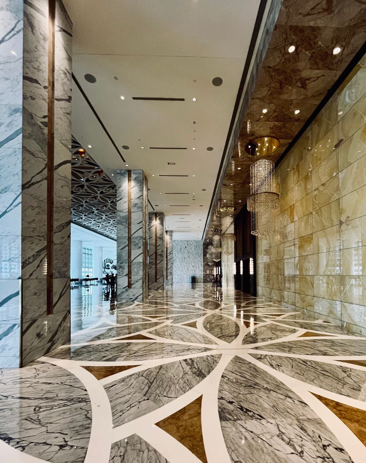 Hotel lobby with a polished marble floor and elegant chandeliers