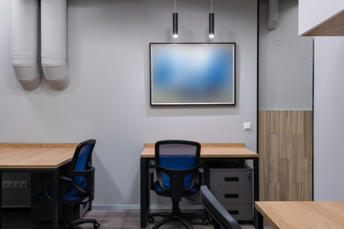 Office desk with a blue chair, a framed picture, and light wood panelling